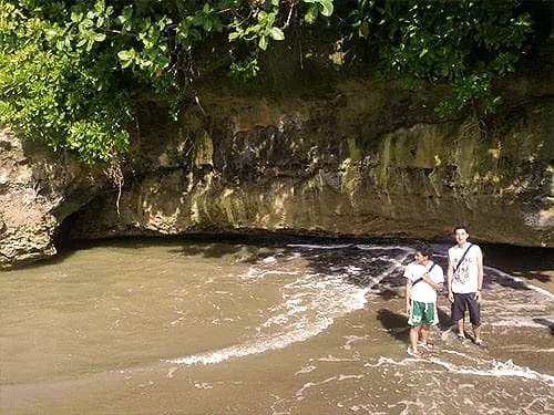 Pantai sempit di antara tebing karang.